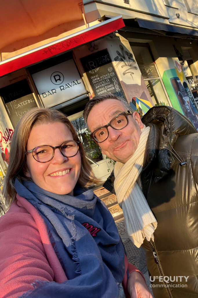 Sione Schmitt-Schillig bon Unequity und Jörg Ziegler von JP Morgan stehen in der Sonne vor einem Cafe in Berlin